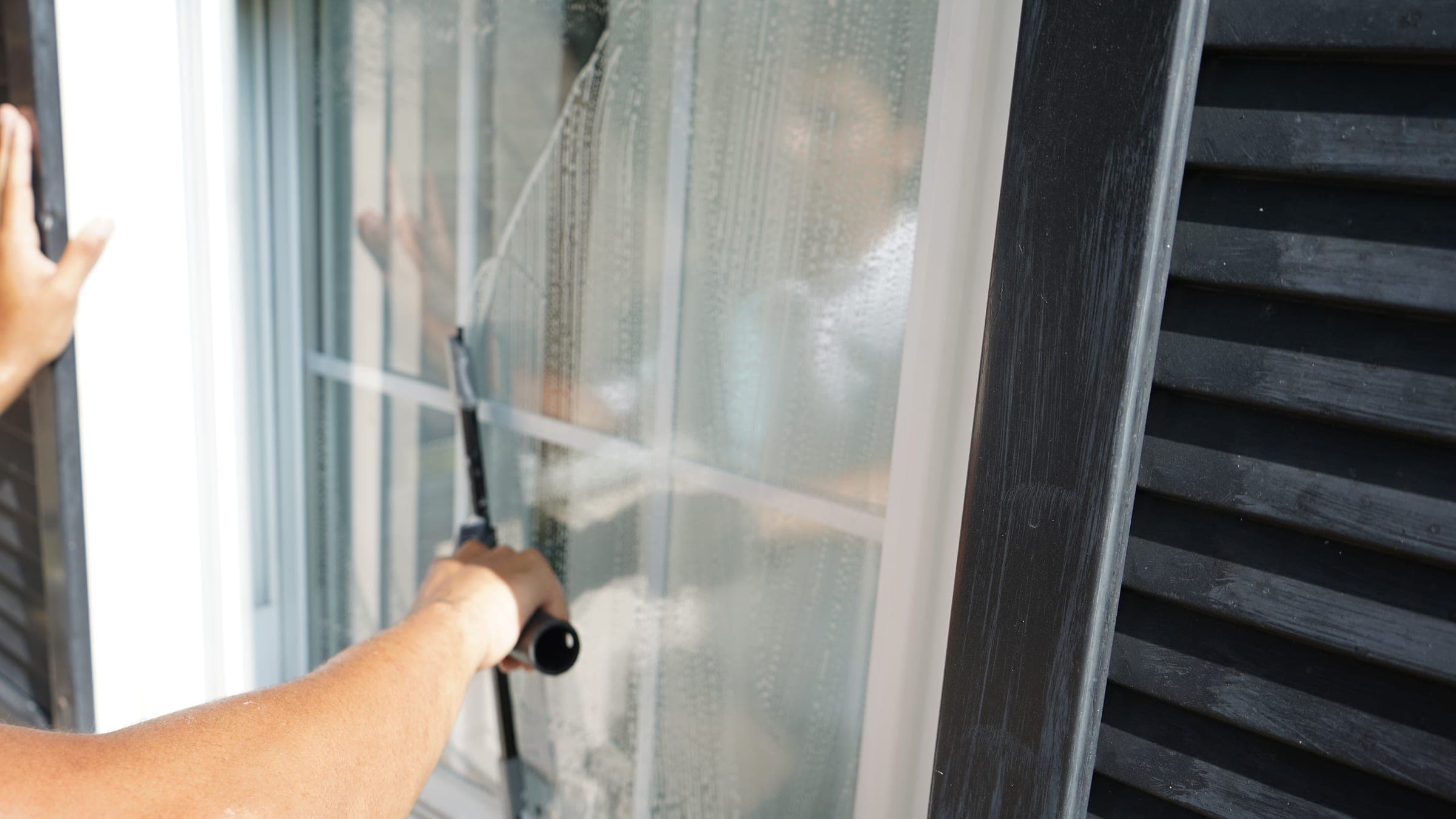 Louie's Window Cleaning technician squeegeeing an exterior window